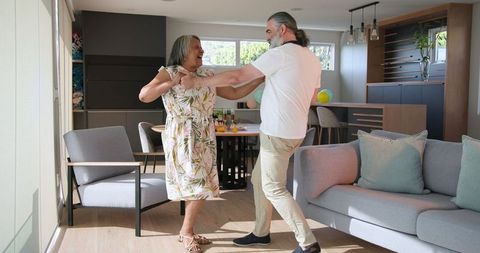 Senior Couple Dancing Joyfully at Home in Modern Living Room