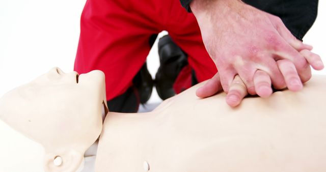 Hands are performing chest compressions on a CPR manikin, demonstrating essential techniques for emergency and life-saving procedures. The image emphasizes healthcare and safety education, ideal for materials on first aid training, medical courses, and emergency response protocols. It highlights hands-on practice crucial for properly administering CPR in real-life situations.