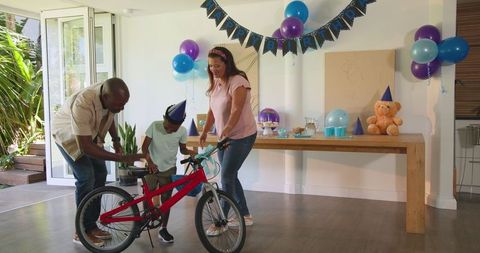 Diverse Family Presenting New Bicycle to Child in Home Birthday Celebration