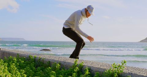 Middle-aged man balancing on beachfront wall with adventure spirit