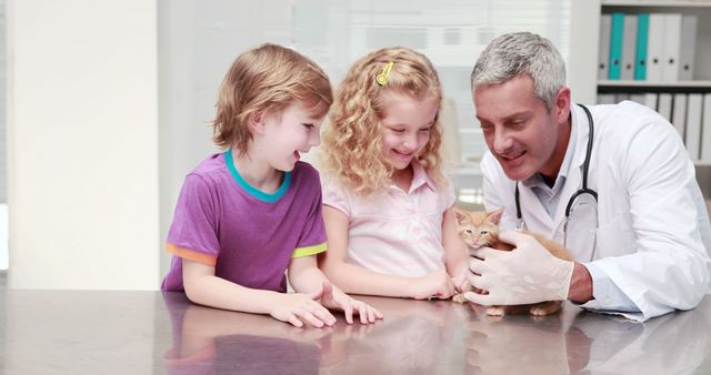Veterinarian showing a small kitten to two happy children at a modern veterinary clinic. The children are smiling and excited to see the kitten. Ideal for topics related to animal care, pediatric services at veterinary clinics, the bond between children and pets, or promotional material for veterinary services.