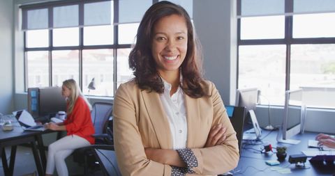 Confident biracial businesswoman office portrait with team in background