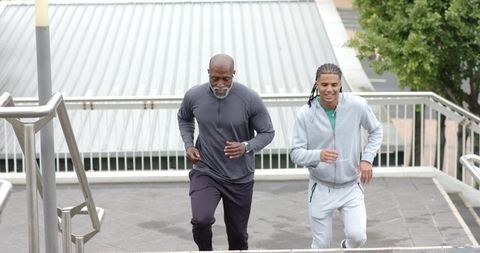 Two men running up urban stairs for endurance training and teamwork motivation