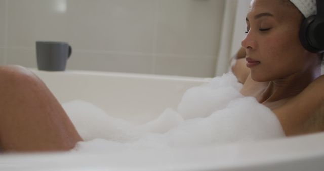 Biracial woman wearing headphones taking a bath and listening to music - Download Free Stock Photos Pikwizard.com