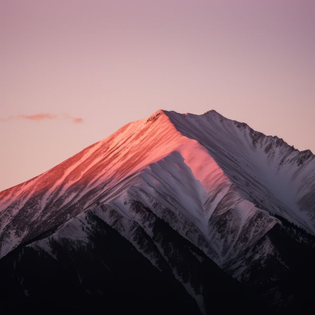 Alpenglow bathes a mountain peak in warm hues, with copy space. Captured at sunset, the image showcases nature's serene beauty in the outdoor setting.