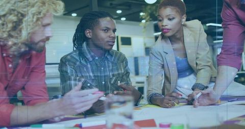 Diverse team collaborating around table in modern coworking office for creative planning