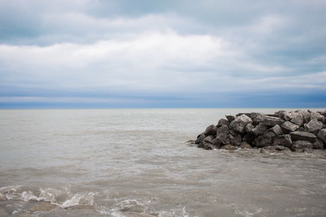 Calm Ocean with Rocky Shoreline Under Overcast Sky - Download Free Stock Photos Pikwizard.com