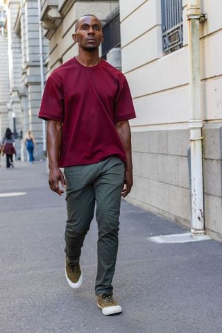 African american man walking downtown in maroon shirt and olive sneakers urban streetwear