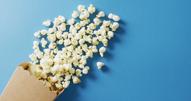 Popcorn Spilling From Box on Blue Background - Download Free Stock Images Pikwizard.com