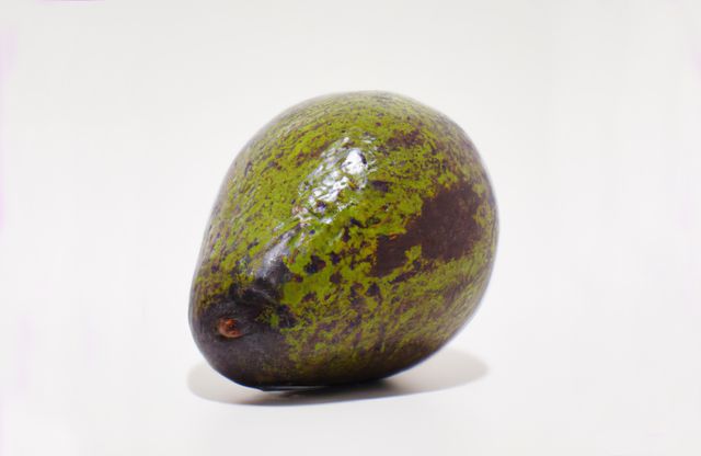 This close-up image of a single ripe avocado placed on a white background highlights the vibrant green and brown colors of the fruit. The image showcases the natural texture and fresh appearance of the avocado, making it ideal for use in food blogs, healthy eating articles, culinary websites, and nutritional guides. The simple white background ensures the focus stays entirely on the avocado, making it perfect for advertising and promotional materials related to organic and vegetarian lifestyles.