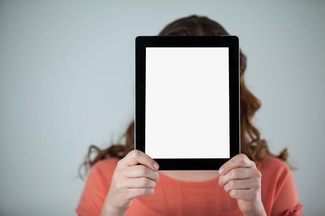 Woman holding a digital tablet in front of her face