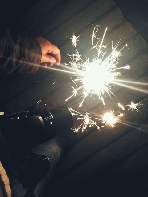 Person holding sparkler at night with camera in hand - Download Free Stock Photos Pikwizard.com