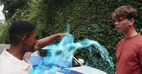 Young men casting swirling blue energy blast on suburban driveway with sports car
