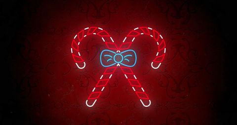 Festive candy canes with neon bow on red background