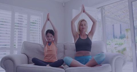 Mother and Daughter Meditating on Couch in Living Room