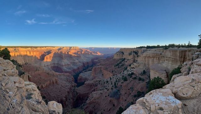Sunset light casting warm glow across stratified high-desert canyon rim
