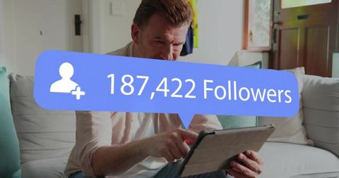 Mature man gaining online followers while scrolling tablet on couch in living room