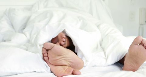 Relaxed Feet Under Cozy White Duvet Indicating Comfort