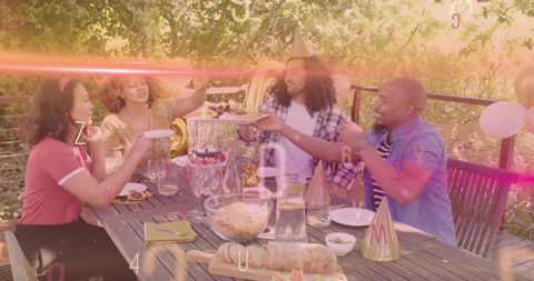 Sunlit backyard celebration passing plate friends sharing bread and drinks party hats
