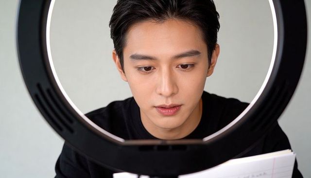 Asian man rehearsing on smartphone with ring light, close-up vlogger portrait
