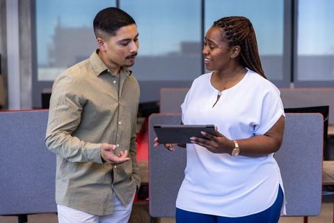 Diverse coworkers collaborating on digital tablet in office