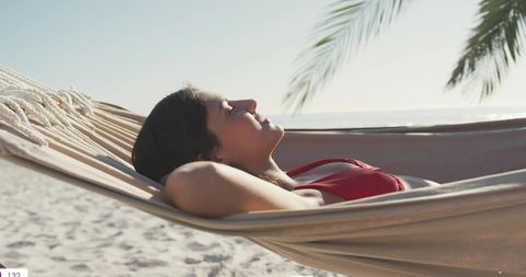 Woman Relaxing in Hammock on Tropical Beach Wearing Red Bikini Top Soaking Sunlight, Serene Seaside
