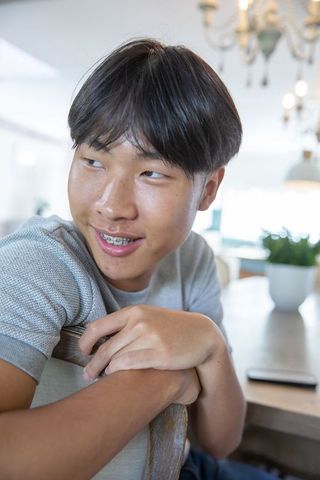 Asian teen smiling relaxed in modern dining room