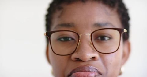 Confident african woman wearing brown framed glasses and gold earrings close-up