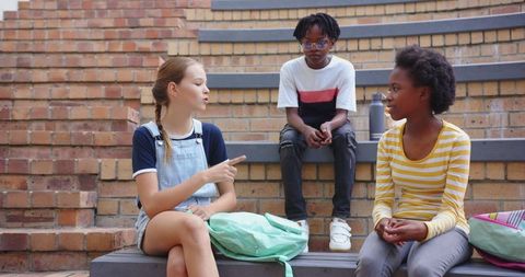 Diverse group of friends discussing school work on brick steps