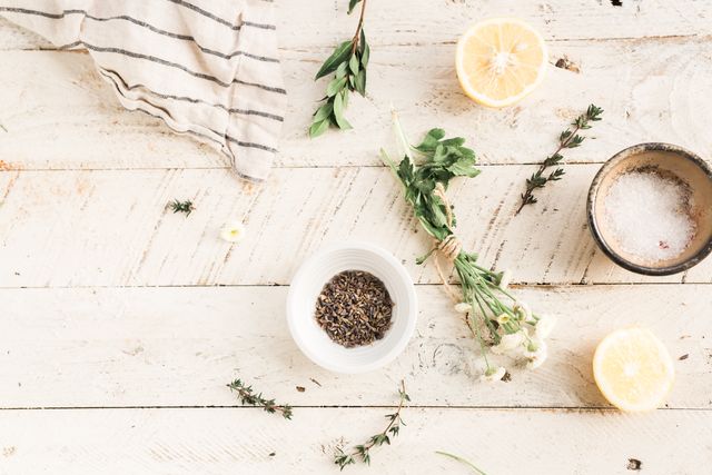 Herbs, spices, and citrus halves arranged on a rustic white wooden surface. Perfect for food blogs, recipe websites, or cooking magazines to highlight natural ingredients and rustic kitchen settings.