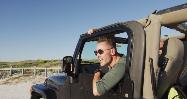 Young man in an open-top jeep, enjoying a scenic drive along the beach on a sunny day. Useful for promoting vacation destinations, outdoor adventures, travel experiences, freedom, and lifestyle concepts.