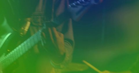 Female guitarist strumming guitar under green stage lights with motion blur and haze