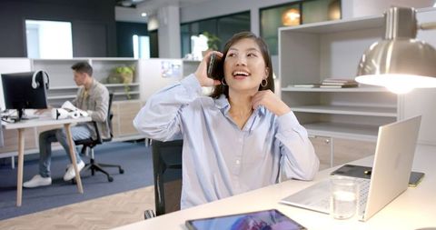 Businesswoman Laughing While Talking on Smartphone in Modern Office