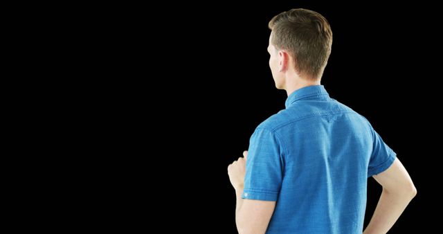 Man standing with his back facing, wearing a blue shirt and holding hand to chin in a contemplative pose. Useful for illustrating concepts of decision making, thinking, concentration, and isolation. Ideal for business, creativity, lifestyle, or personal reflection themes.