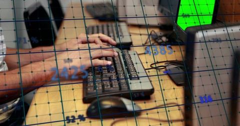 Hands typing on keyboard at workstation with data grid overlay and analytics
