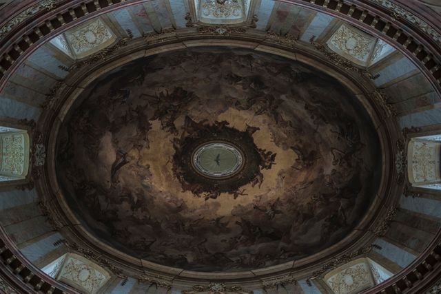 Detailed fresco on a domed ceiling showcasing intricate artwork and stylistic elements typical of classical and baroque architecture. Ideal for use in travel brochures, historical references, cultural heritage advertisements, or educational materials about classical art and architecture.