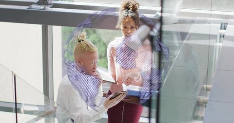 Colleagues collaborating on tablet and binder in modern glass atrium with purple globe overlay