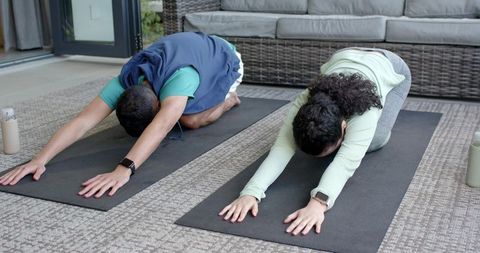 Couple Practicing Yoga Child's Pose in Zen Sunroom