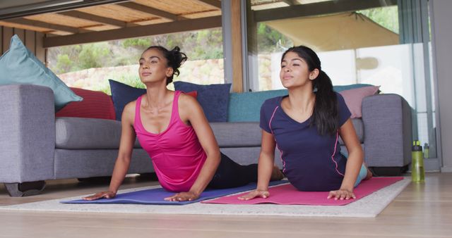 Image of happy diverse female friends practicing yoga together at home. Friendship, spending quality time together at home.