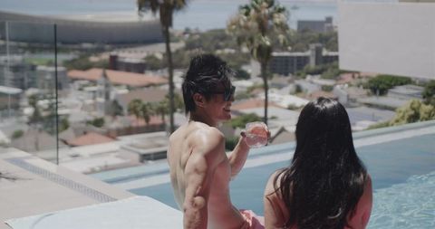 Sunny rooftop infinity pool couple sipping cocktails, enjoying city skyline and ocean views
