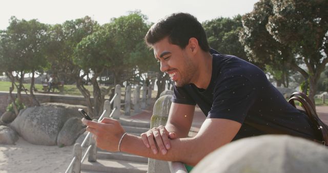 Young Man Smiling While Using Smartphone at Beach - Download Free Stock Images Pikwizard.com