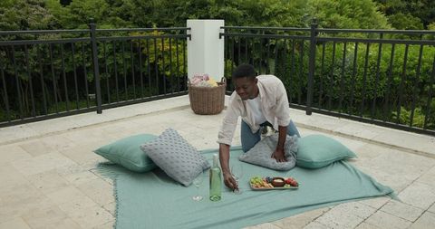 Man Organizing Elegant Picnic on Terrace with Wine and Snacks