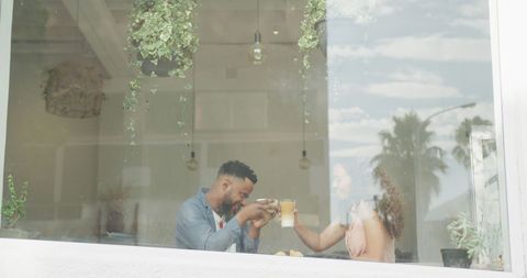 Happy Couple Enjoying Coffee at Indoor Cafe by Window