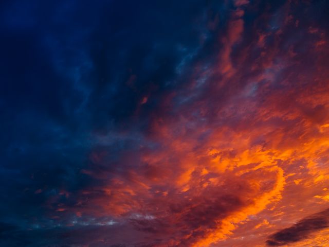 Dramatic sunset sky with fiery clouds showcasing vibrant colors of orange, red, and dark blue in twilight. Ideal for backgrounds, landscape themes, nature blog articles, inspirational social media posts, and wall art decor.