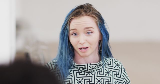 The woman with blue hair seems visibly animated, likely in casual conversation or a light argument. Her attire is laid-back, making this suitable for themes of casual life, youth culture, and body modifications. Use this to reflect informal discussions, personal blogs, lifestyle articles, or social interactions.