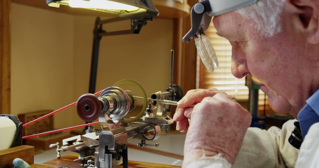 Elderly man deeply focused while working on a lathe machine in a well-lit workshop. Ideal for illustrating themes of skilled labor, craftsmanship, precision work, and the dedication of experienced individuals. Suitable for content related to engineering, mechanical work, trade skills, and nostalgic homage to traditional manual labor.