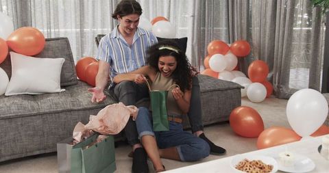 Joyful Couple Exchanging Gifts in Living Room for Birthday Celebration