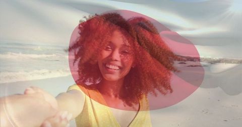 Smiling woman holding hand on sunlit beach with colorful overlay and lens flare