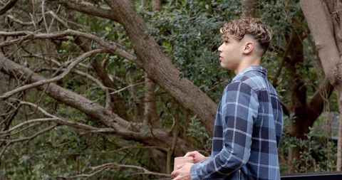 Man in Plaid Shirt Holding Mug in Woodland Setting