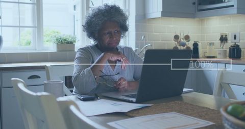 Senior Woman Engaged in Financial Analysis on Laptop in Modern Kitchen